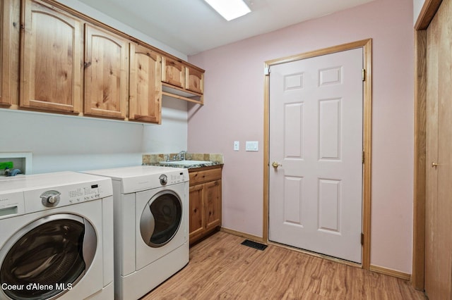 laundry room with cabinets, washing machine and dryer, light hardwood / wood-style floors, and sink