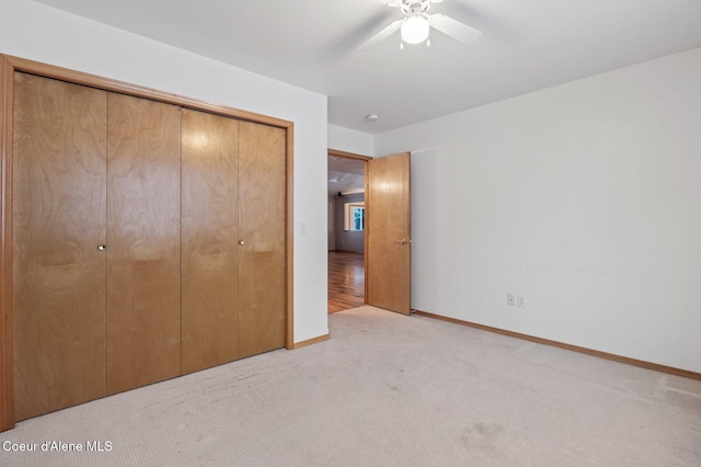 unfurnished bedroom with light colored carpet, a closet, and ceiling fan