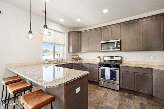 kitchen with a kitchen breakfast bar, stainless steel appliances, pendant lighting, and kitchen peninsula