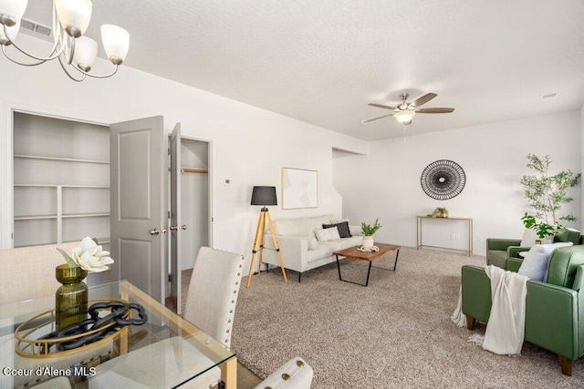 living room featuring ceiling fan with notable chandelier, a textured ceiling, and carpet flooring