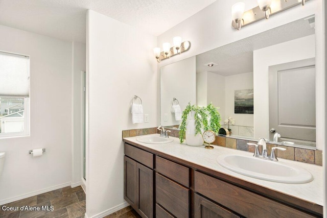 bathroom featuring a textured ceiling, a wealth of natural light, an enclosed shower, and vanity