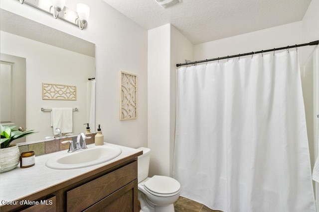 bathroom featuring toilet, vanity, and a textured ceiling