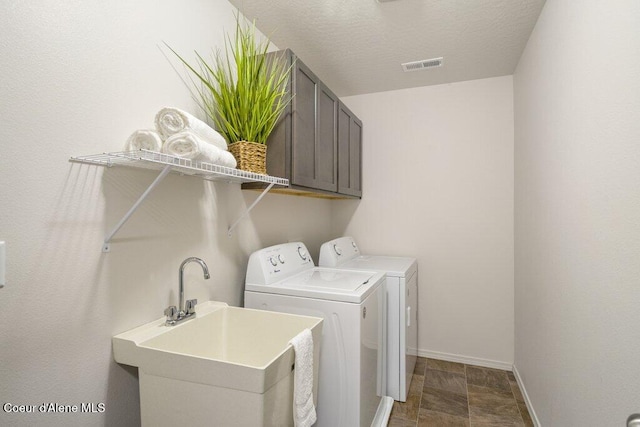 laundry room with cabinets, a textured ceiling, sink, and independent washer and dryer