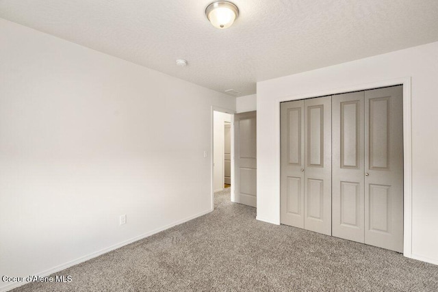 unfurnished bedroom featuring carpet floors, a closet, and a textured ceiling