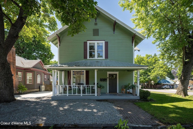 rear view of property featuring covered porch and a lawn