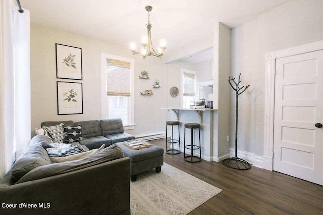 living room featuring dark wood-type flooring, a chandelier, and baseboard heating