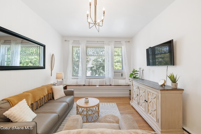 living room featuring a baseboard heating unit, an inviting chandelier, light wood-type flooring, and a wealth of natural light