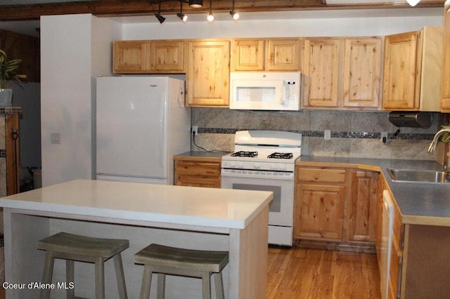 kitchen featuring a sink, white appliances, light wood-type flooring, a kitchen island, and a kitchen bar