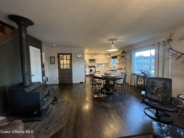 dining space featuring dark hardwood / wood-style flooring and a wood stove