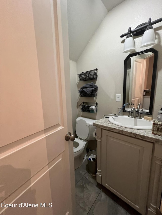 bathroom with lofted ceiling, toilet, and vanity