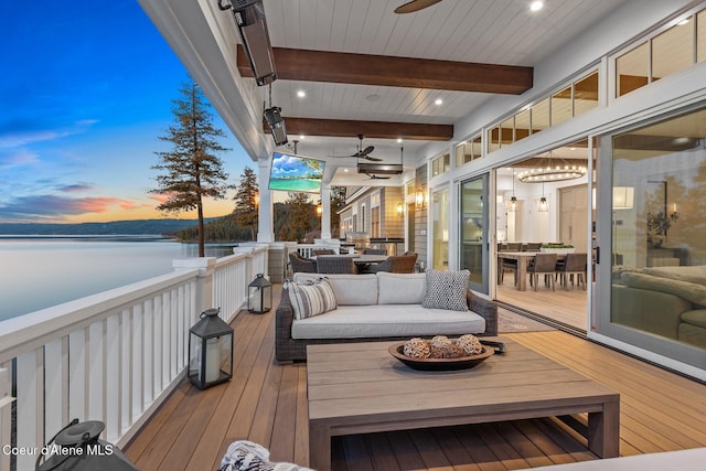 deck at dusk with an outdoor hangout area and a water view