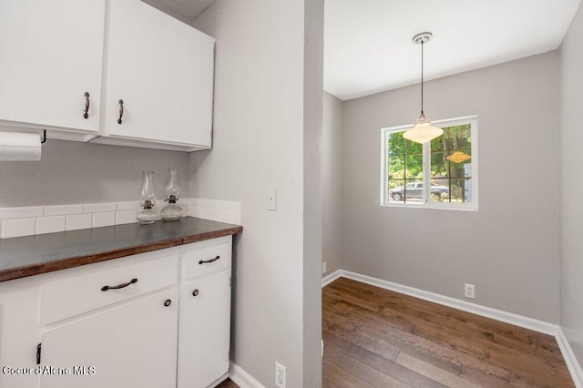 kitchen featuring wood-type flooring, white cabinets, and decorative light fixtures