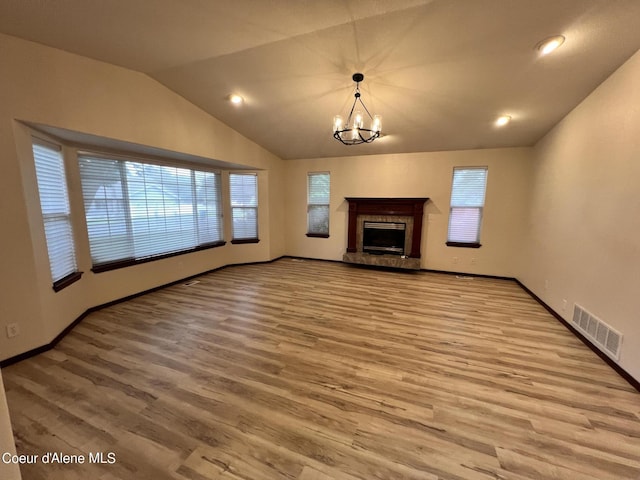 unfurnished living room featuring light hardwood / wood-style flooring, an inviting chandelier, and vaulted ceiling