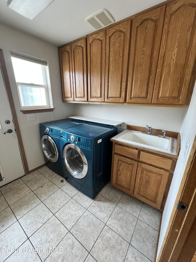 clothes washing area featuring sink, washer and dryer, light tile patterned floors, and cabinets