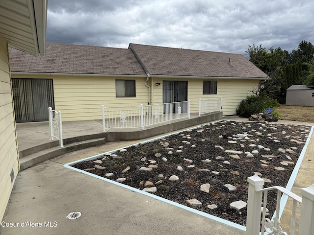 6344 N Colfax St, Dalton Gardens, ID 83815 - rear view of house with a patio area, a storage unit, and a shingled roof