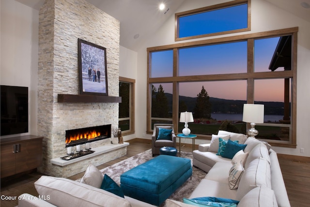 living room featuring a stone fireplace, high vaulted ceiling, and wood-type flooring