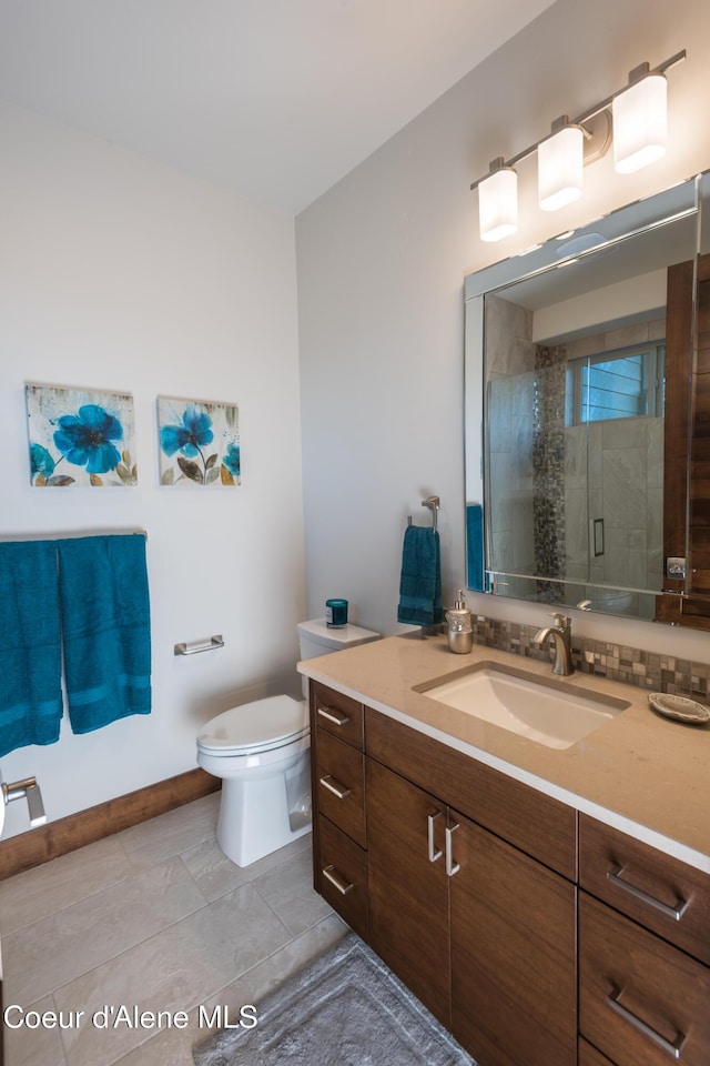 bathroom with tile patterned floors, vanity, toilet, and a shower with door