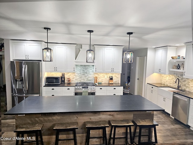 kitchen featuring hanging light fixtures, custom exhaust hood, appliances with stainless steel finishes, and a kitchen island