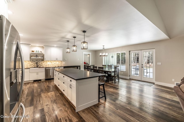 kitchen with decorative backsplash, a breakfast bar, open shelves, appliances with stainless steel finishes, and dark countertops