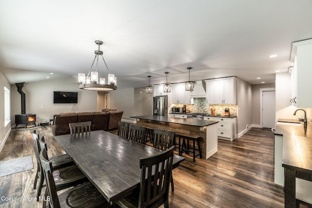 dining space with recessed lighting, baseboards, a wood stove, a notable chandelier, and dark wood-type flooring