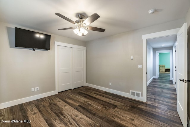 unfurnished bedroom with baseboards, visible vents, dark wood-style flooring, and a closet