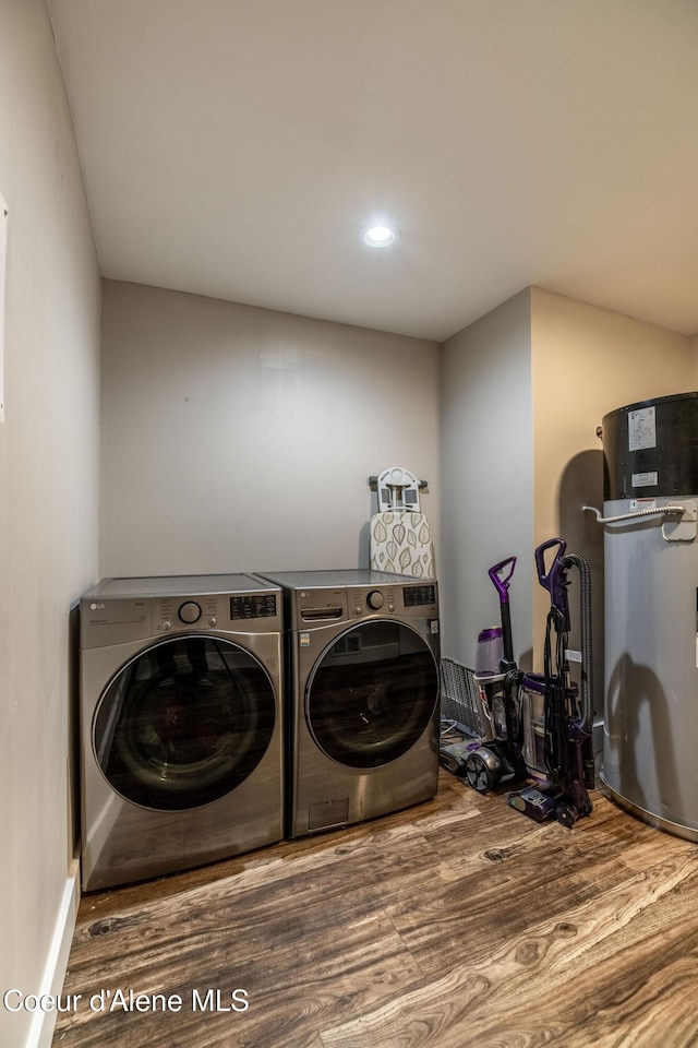 clothes washing area featuring recessed lighting, wood finished floors, water heater, laundry area, and washing machine and dryer