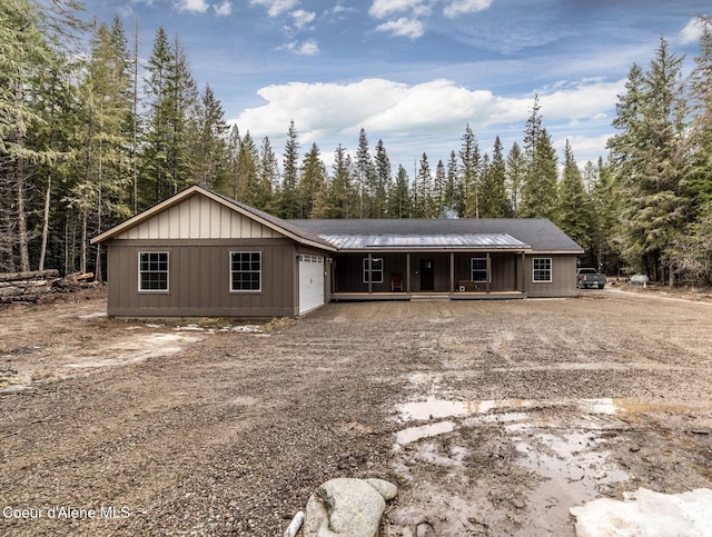ranch-style house with a garage, a porch, board and batten siding, and driveway