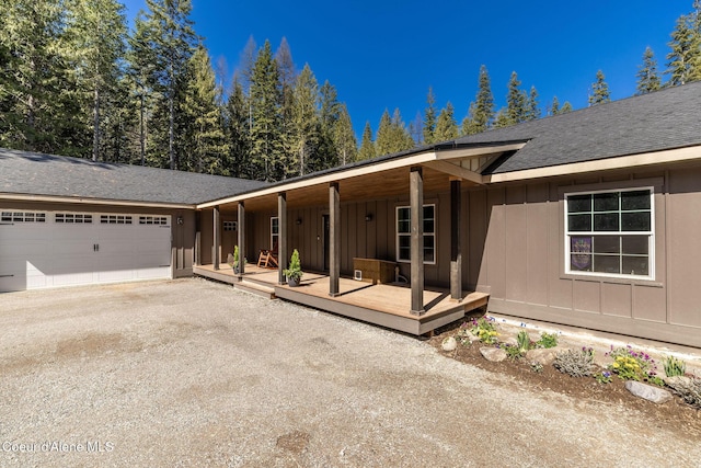 view of front facade with driveway, board and batten siding, a deck, a shingled roof, and an attached garage