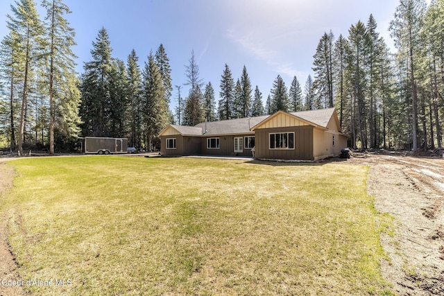 rear view of house featuring board and batten siding and a yard