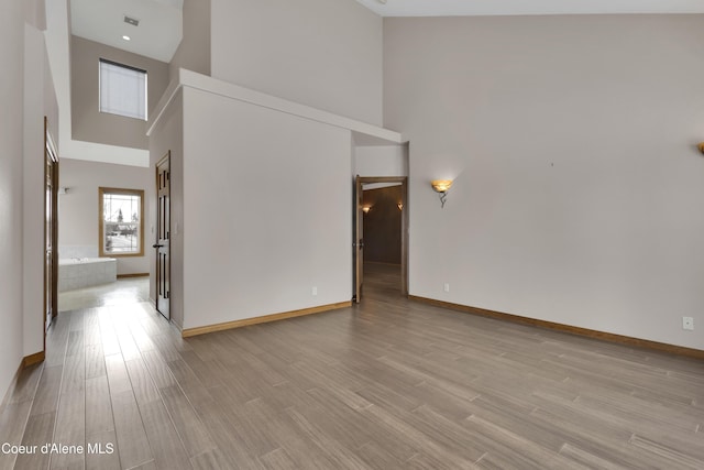 unfurnished room with a high ceiling and light hardwood / wood-style flooring