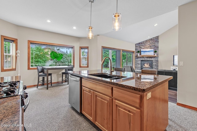 kitchen featuring light carpet, appliances with stainless steel finishes, sink, hanging light fixtures, and an island with sink