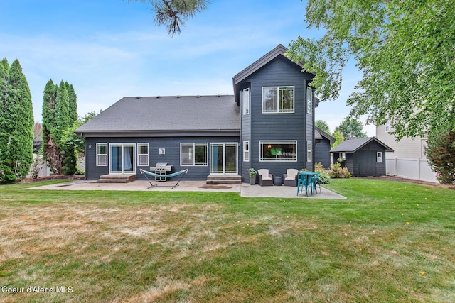 rear view of house featuring a lawn, a shed, and a patio