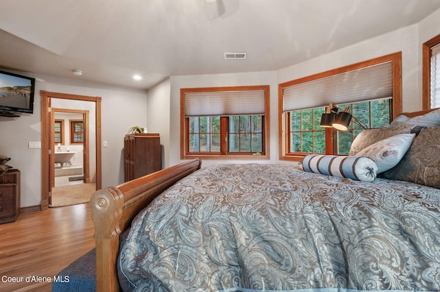 bedroom featuring ensuite bathroom and light hardwood / wood-style flooring