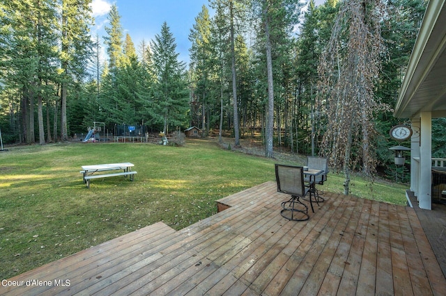 wooden deck featuring a lawn, a playground, and a trampoline