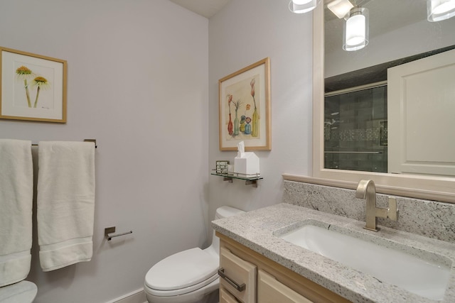 bathroom with an enclosed shower, vanity, and toilet