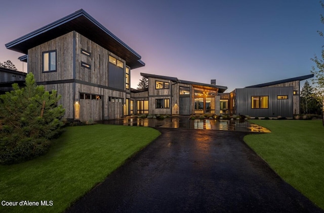 back house at dusk featuring a lawn