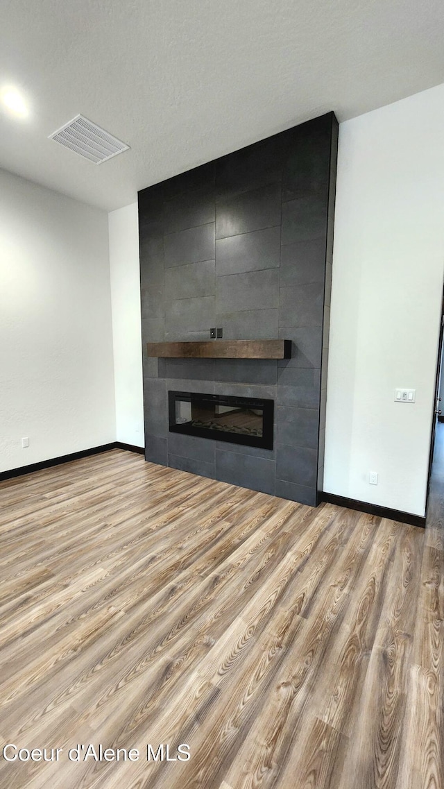 unfurnished living room featuring a large fireplace and light wood-type flooring