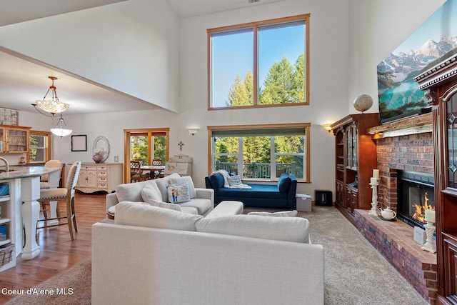 carpeted living room featuring a towering ceiling and a brick fireplace