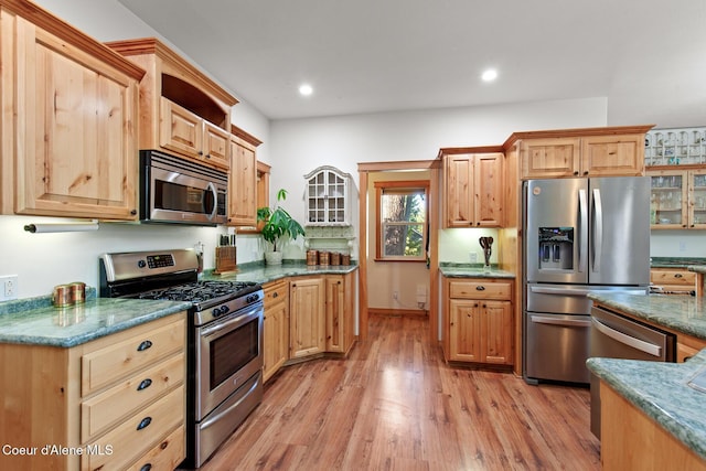 kitchen featuring dark stone countertops, light brown cabinetry, stainless steel appliances, and light hardwood / wood-style floors