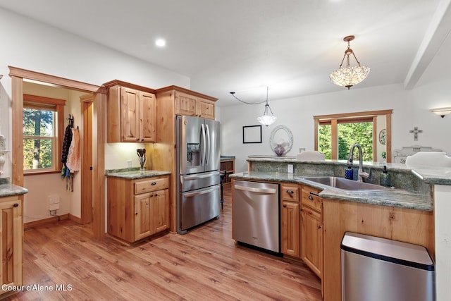 kitchen with appliances with stainless steel finishes, sink, decorative light fixtures, a chandelier, and light hardwood / wood-style floors