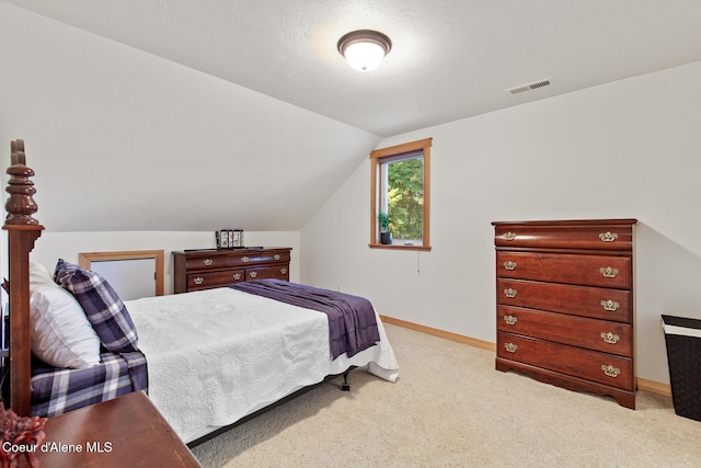 bedroom featuring a textured ceiling, light colored carpet, and lofted ceiling