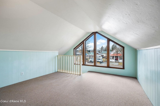 bonus room with lofted ceiling, carpet floors, and wood walls