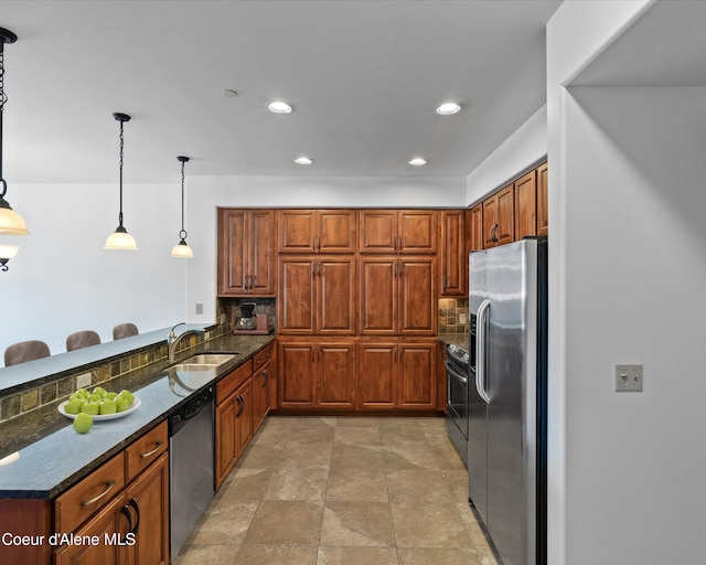 kitchen featuring stainless steel appliances, sink, dark stone countertops, backsplash, and pendant lighting