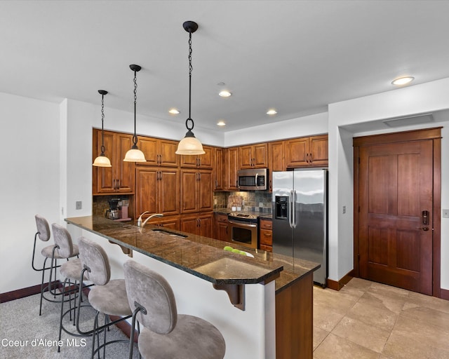 kitchen with stainless steel appliances, sink, kitchen peninsula, backsplash, and pendant lighting