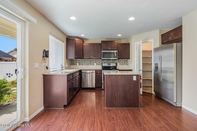 1449 N Moonstone St, Post Falls, ID 83854 - kitchen featuring appliances with stainless steel finishes, dark wood-style flooring, a kitchen island, tasteful backsplash, and recessed lighting