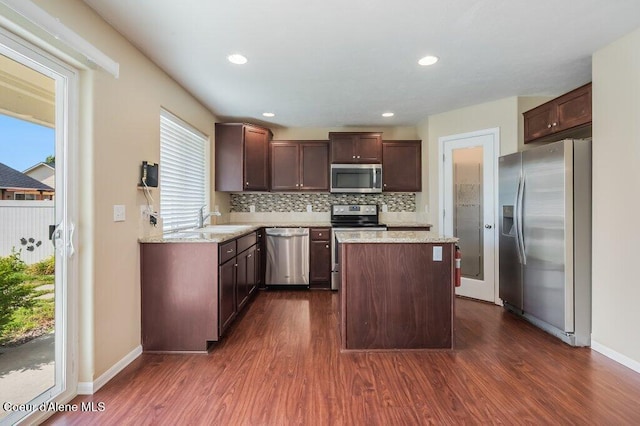 1449 N Moonstone St, Post Falls, ID 83854 - kitchen with appliances with stainless steel finishes, dark wood finished floors, a center island, tasteful backsplash, and dark brown cabinets