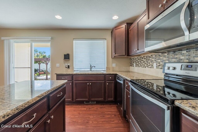 1449 N Moonstone St, Post Falls, ID 83854 - kitchen featuring appliances with stainless steel finishes, dark wood finished floors, tasteful backsplash, light stone countertops, and dark brown cabinetry