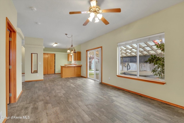 unfurnished living room with hardwood / wood-style flooring and ceiling fan with notable chandelier