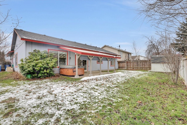 rear view of house with a hot tub and a storage shed