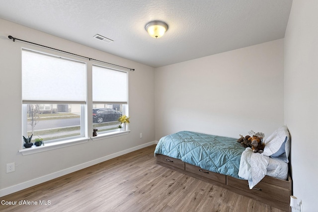 bedroom with a textured ceiling and light hardwood / wood-style floors